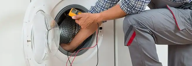 Dryer repair technician inspecting and repairing a clothes dryer in Overland Park, KS
