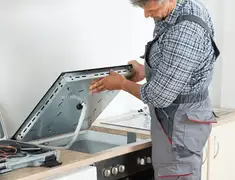 Appliance repair technician installing a built-in cooktop in Overland Park, KS