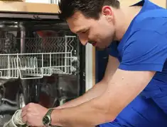 Dishwasher repair technician inspecting and servicing an open dishwasher in Overland Park, KS