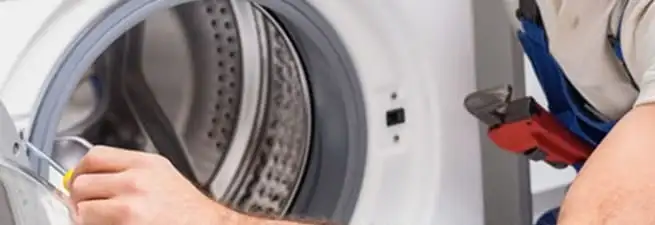 Appliance technician repairing a clothes dryer drum and internal parts in Overland Park, KS