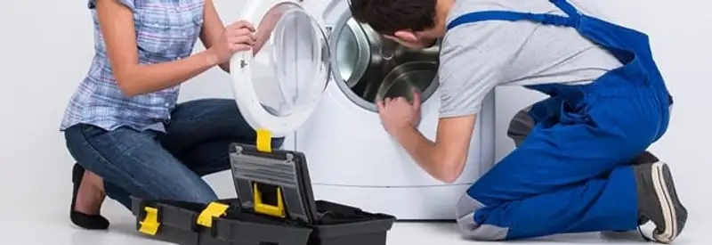 Washer repair technician inspecting a front-load washing machine with tools in Overland Park, KS