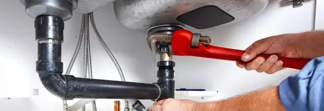 Garbage disposal repair technician tightening the sink drain and disposal connection in Overland Park, KS