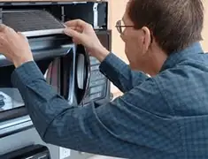 Appliance repair technician replacing a microwave vent filter in Overland Park, KS