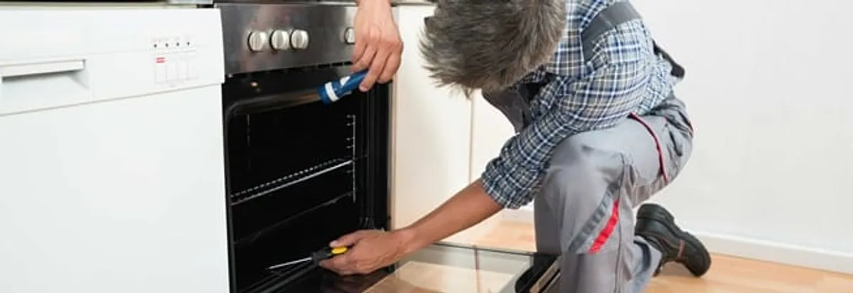 Oven repair technician inspecting and servicing an electric oven in Overland Park, KS