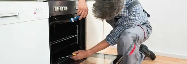 Oven repair technician inspecting and servicing an electric oven in Overland Park, KS