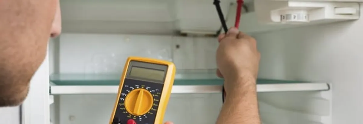 Refrigerator repair technician testing electrical components with a multimeter in Overland Park, KS