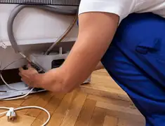Appliance repair technician fixing refrigerator water line and connections in Overland Park, KS