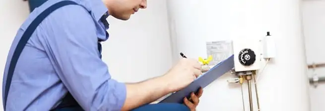 Water heater repair technician inspecting the unit and recording service notes in Overland Park, KS