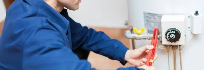 Water heater repair technician adjusting the temperature control and gas valve in Overland Park, KS